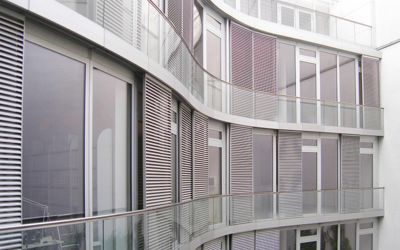 Eine wellenförmige Fassade eines futuristisch gebauten Bürogebäudes in Berlin. Riesige großflächige Fenster. Schiebetüren mit Lamellen sollen vor Sonnenlicht schützen. Die professionell und gewissenhaft bewertete Immobilie bietet modernsten Ausstattung.